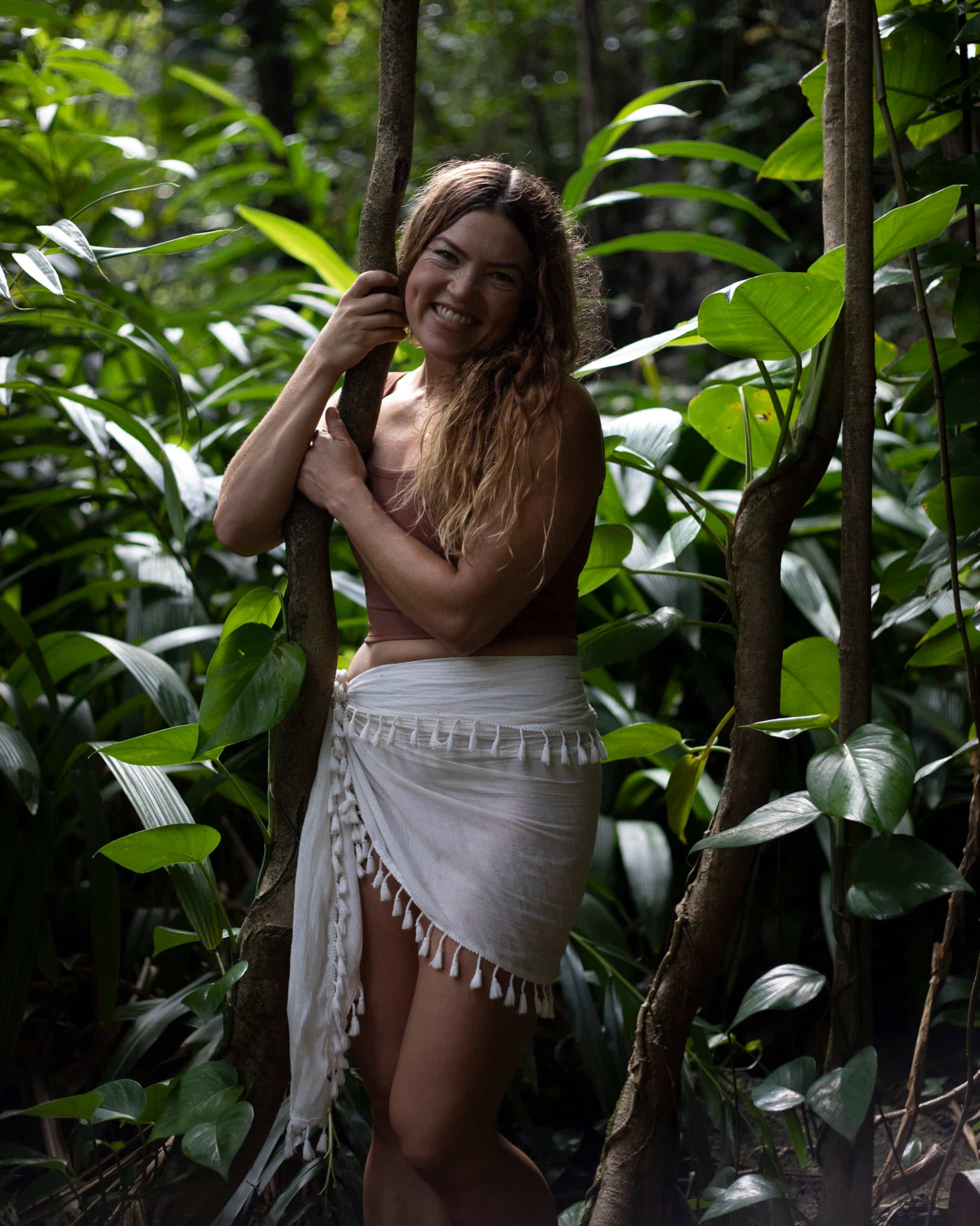 Meghan Mahealani standing smiling in a tropical jungle in the trees.